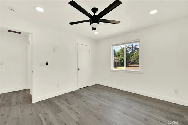 an empty room with wooden floor and a ceiling fan