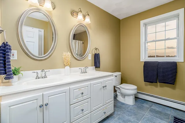 a bathroom with a toilet a sink a mirror and a window