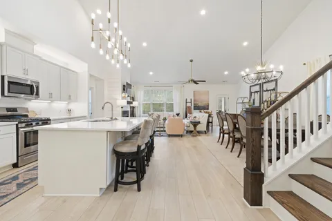 a large white kitchen with lots of counter space and chandelier