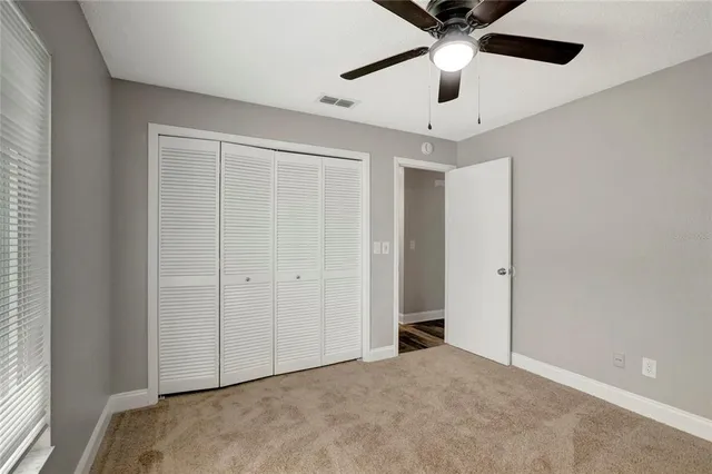 an empty room with chandelier fan and windows