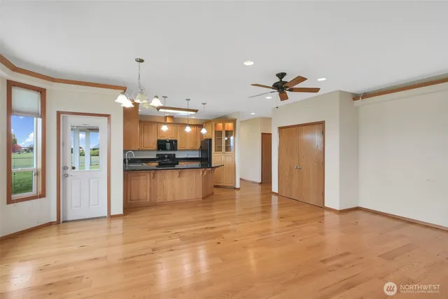 a view of an empty room with wooden floor and a kitchen