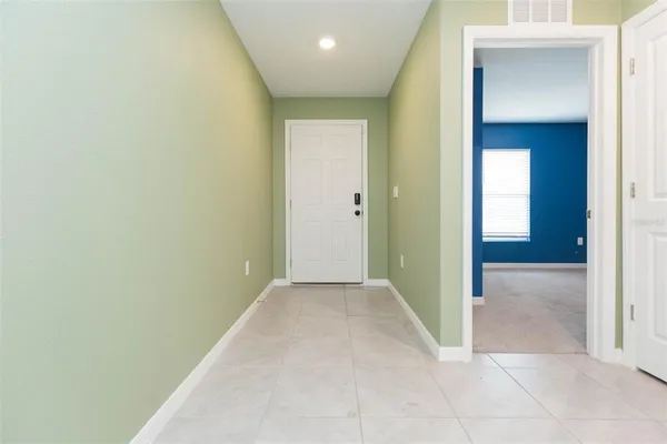 a view of hallway with an empty room and wooden floor