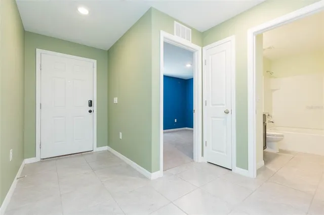 an empty room and a bathroom with a glass door