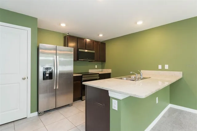 a kitchen with stainless steel appliances granite countertop a sink a stove a refrigerator with a dining table and chairs