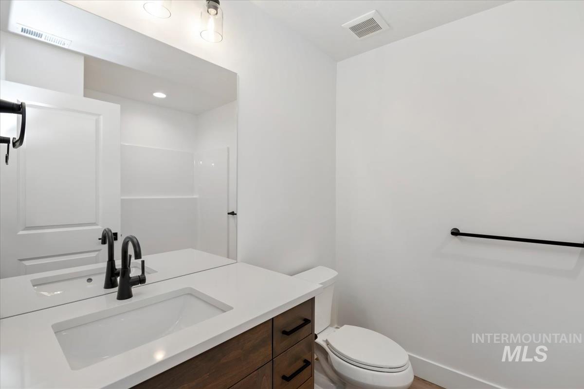 768 South Calhoun Lane Star, ID 83669 - Photo 29 of 36 Contemporary bathroom featuring a wood-finish vanity with an integrated sink, matte black faucet, and a large wall-mounted mirror