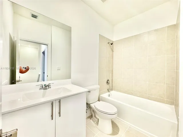 a bathroom with a bathtub shower sink vanity mirror and toilet