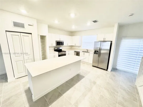 a large white kitchen with stainless steel appliances a refrigerator a stove a microwave a sink and dishwasher
