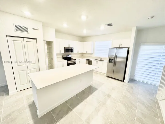 a large white kitchen with stainless steel appliances a refrigerator a stove a microwave a sink and dishwasher