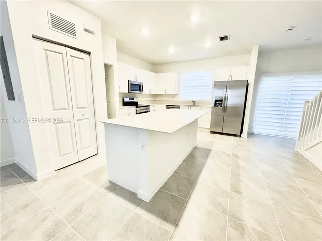 a large white kitchen with a sink dishwasher a refrigerator and cabinets