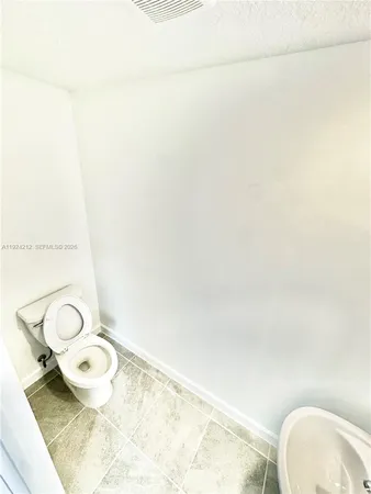 a bathroom with a granite countertop toilet and a sink