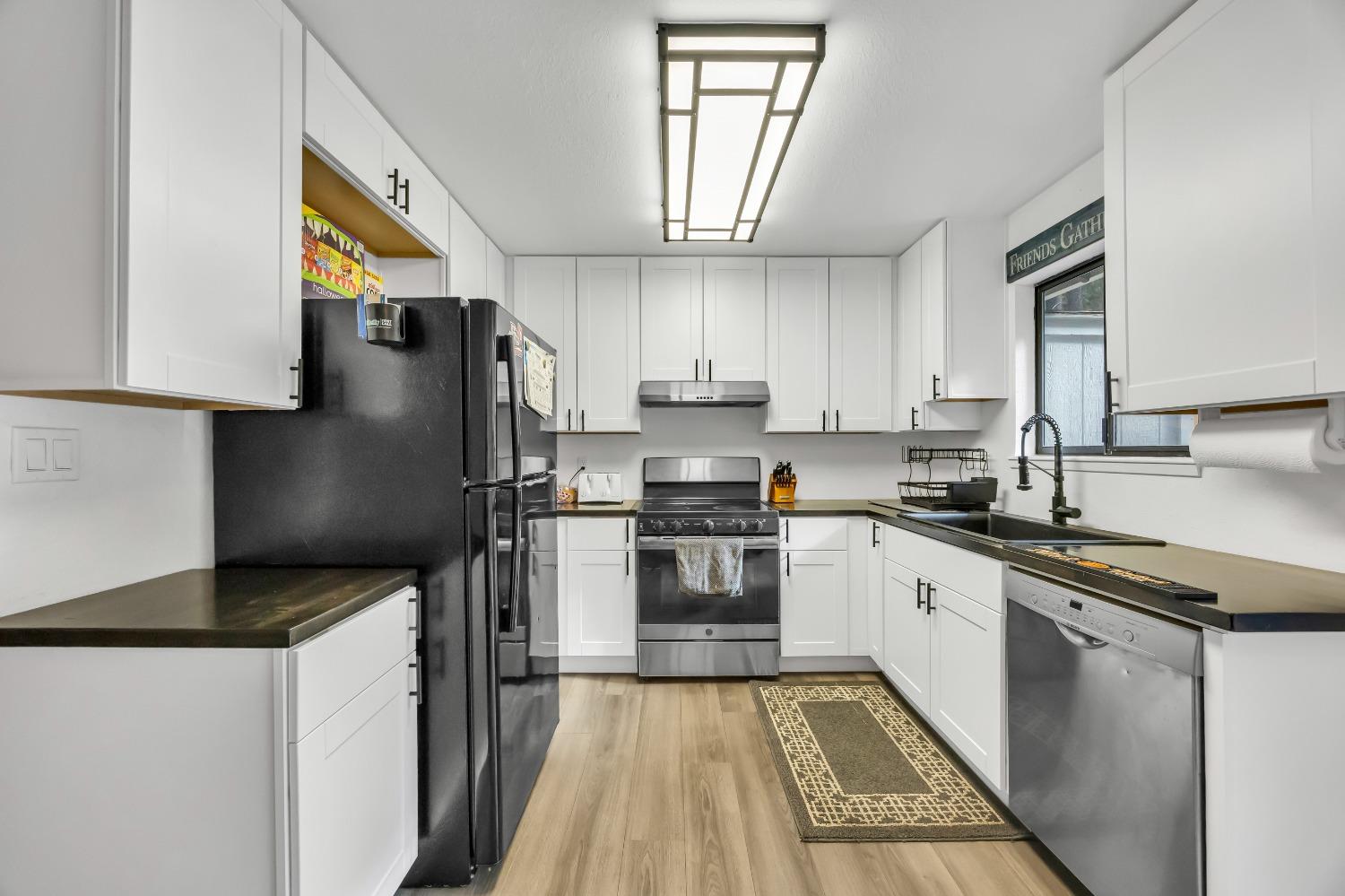 6922 Ridgeway Drive Pollock Pines, CA 95726 - Photo 15 of 44 a kitchen with granite countertop a refrigerator a sink dishwasher a stove and white cabinets with wooden floor