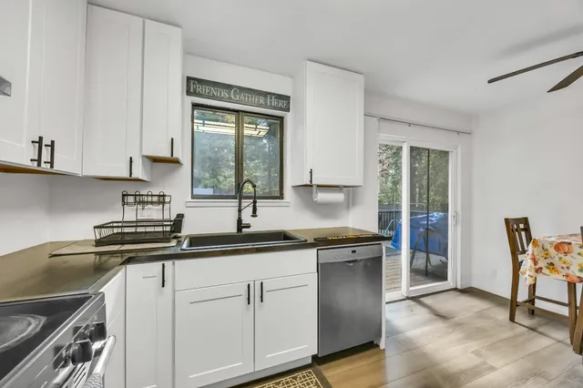 a kitchen with stainless steel appliances granite countertop white cabinets a stove a sink and dishwasher