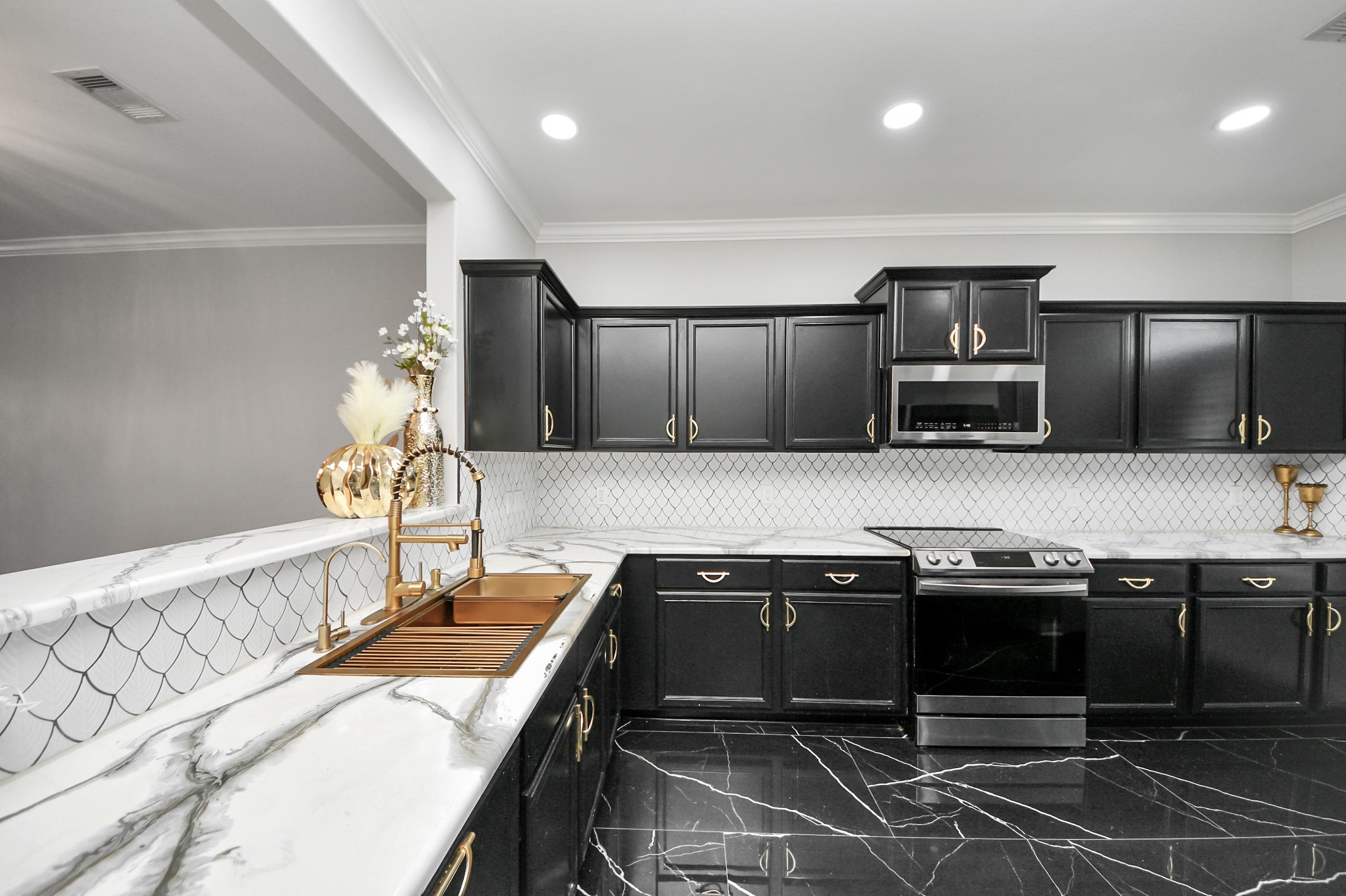 6931 Primrose Road Baytown, TX 77521 - Photo 7 of 50 Modern kitchen with black cabinetry, marble counters, stainless steel appliances, and a striking gold farmhouse sink overlooking the dining and living areas.