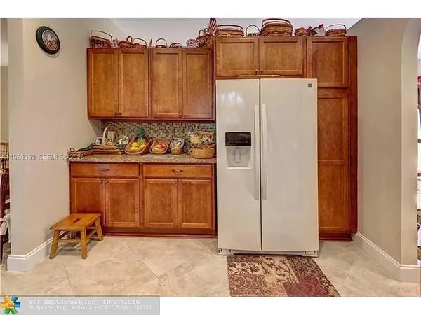 a kitchen with stainless steel appliances granite countertop a refrigerator a stove a sink and white cabinets with wooden floor