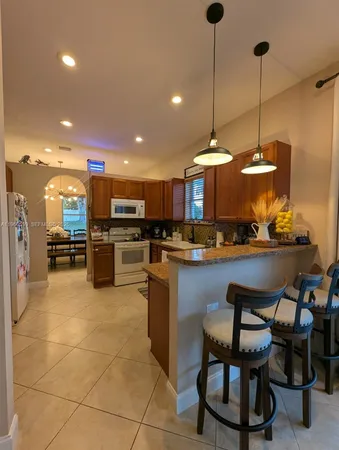 a kitchen with stainless steel appliances kitchen island granite countertop a refrigerator and a sink