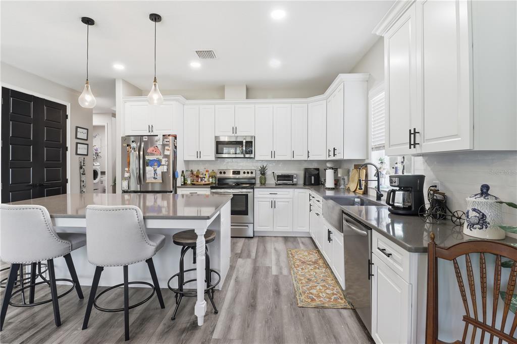 9689 East White Egret Path Inverness, FL 34450 - Photo 11 of 44 a kitchen with stainless steel appliances granite countertop a stove a sink dishwasher a refrigerator and white cabinets with wooden floor