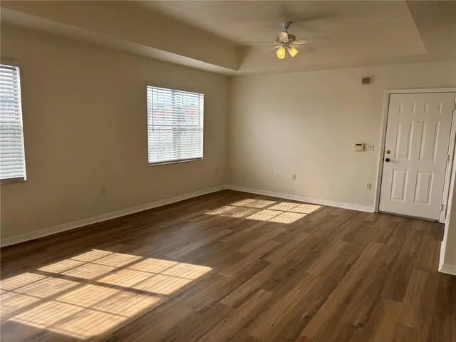 a view of empty room with wooden floor and fan