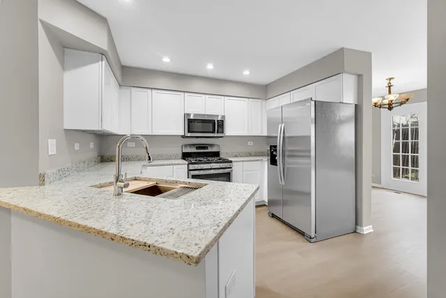 a kitchen with granite countertop a refrigerator a sink a stove a microwave and island