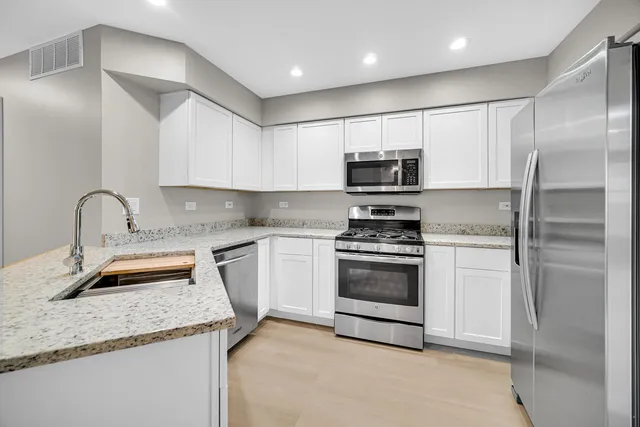 a kitchen with granite countertop a sink stainless steel appliances and cabinets