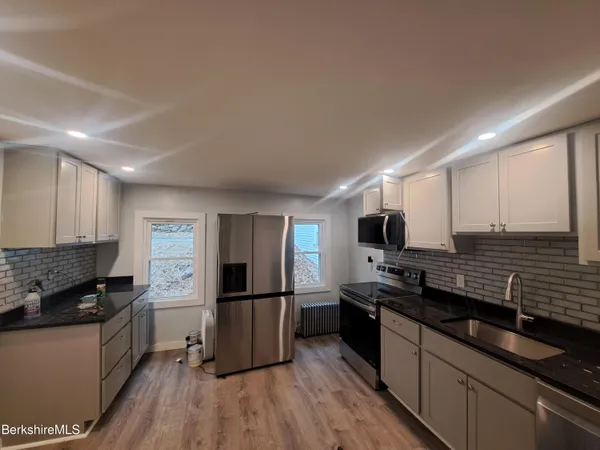 a kitchen with stainless steel appliances kitchen island granite countertop a stove refrigerator and a microwave