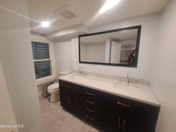 a bathroom with a toilet sink double vanity and mirror