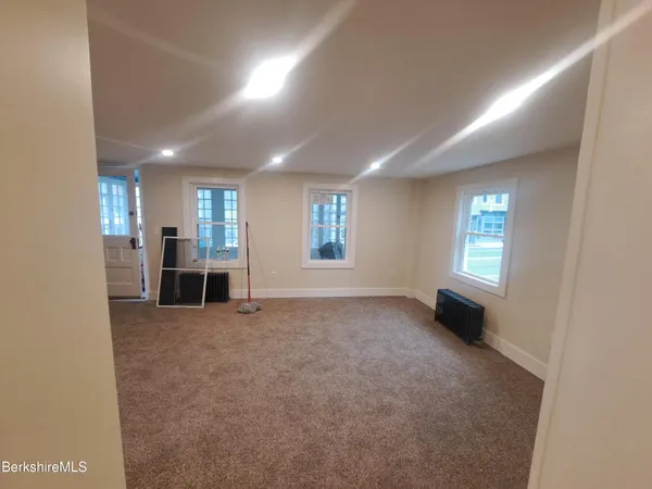 an empty room with windows and fireplace