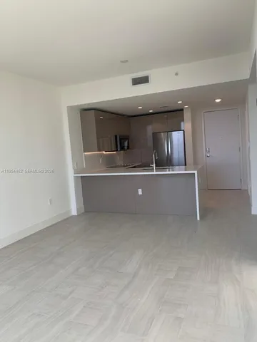 an empty room with kitchen view and a window