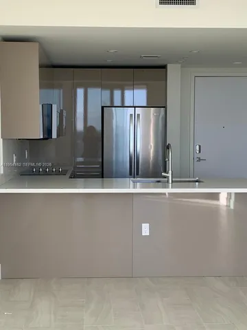 a view of a kitchen with stainless steel appliances kitchen island a refrigerator sink and stove
