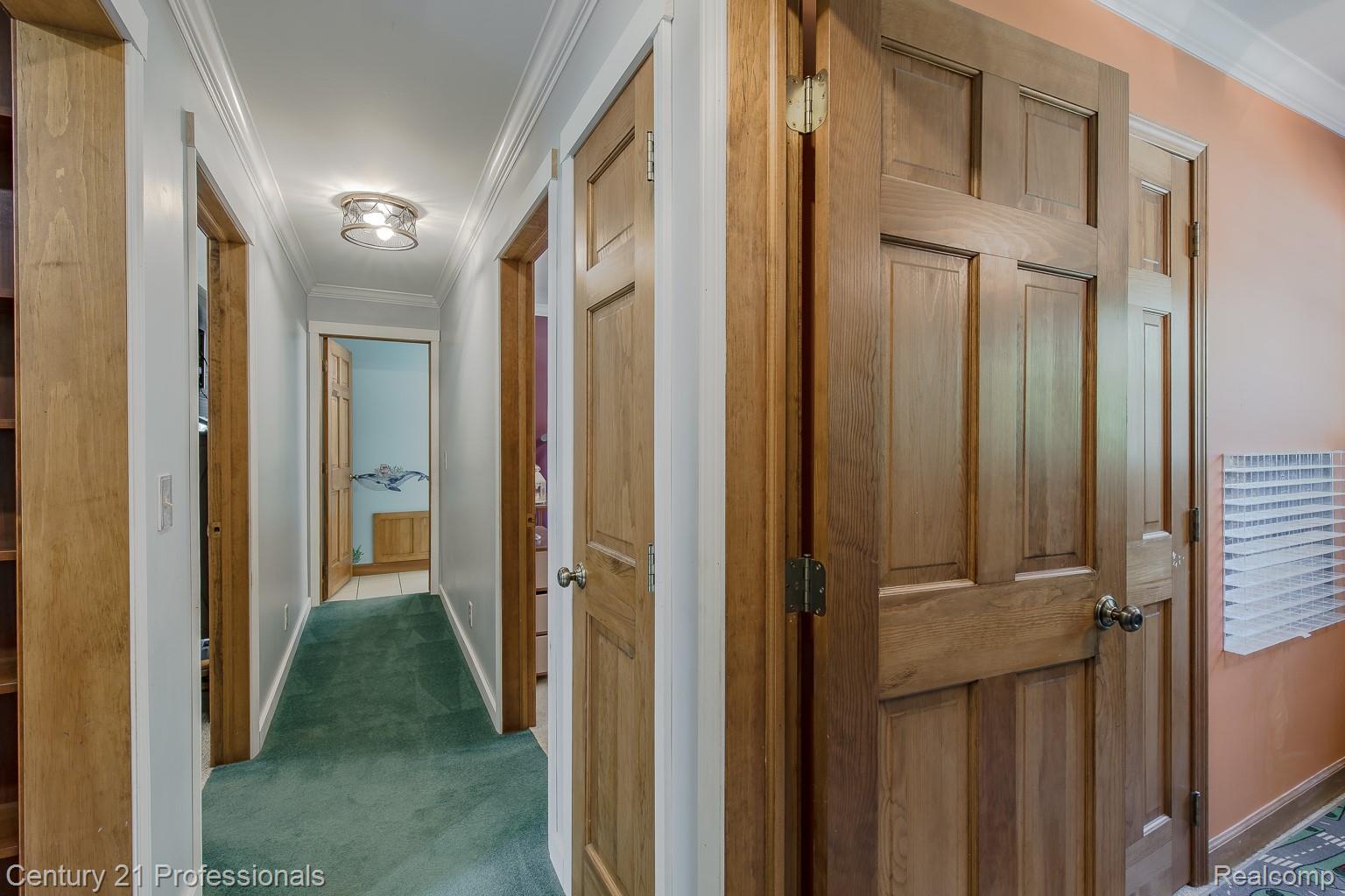 1790 Kent Road Ortonville, MI 48462 - Photo 11 of 64 Hallway featuring solid wood-panel doors, crown molding, a flush-mount ceiling light fixture, and green carpeting
