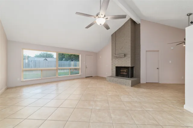 a view of an empty room with a fireplace and a window