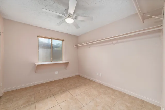 an empty room with a ceiling fan and a window