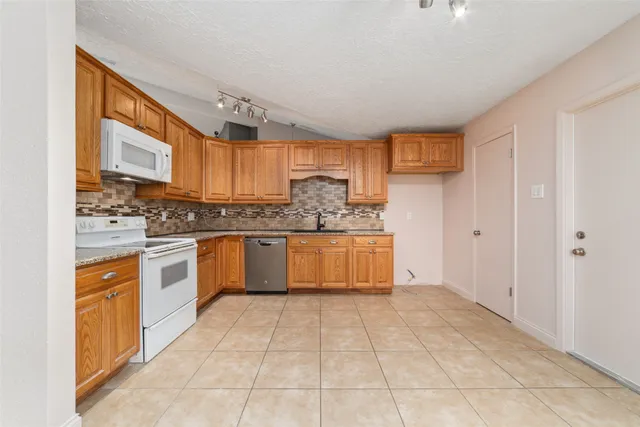 a large kitchen with stainless steel appliances granite countertop a stove a sink dishwasher and a refrigerator