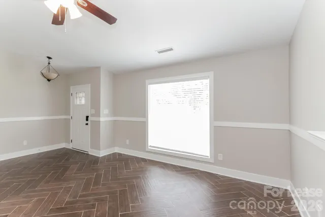 an empty room with ceiling fan and window