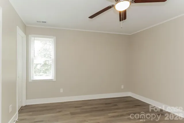 an empty room with wooden floor fan and windows