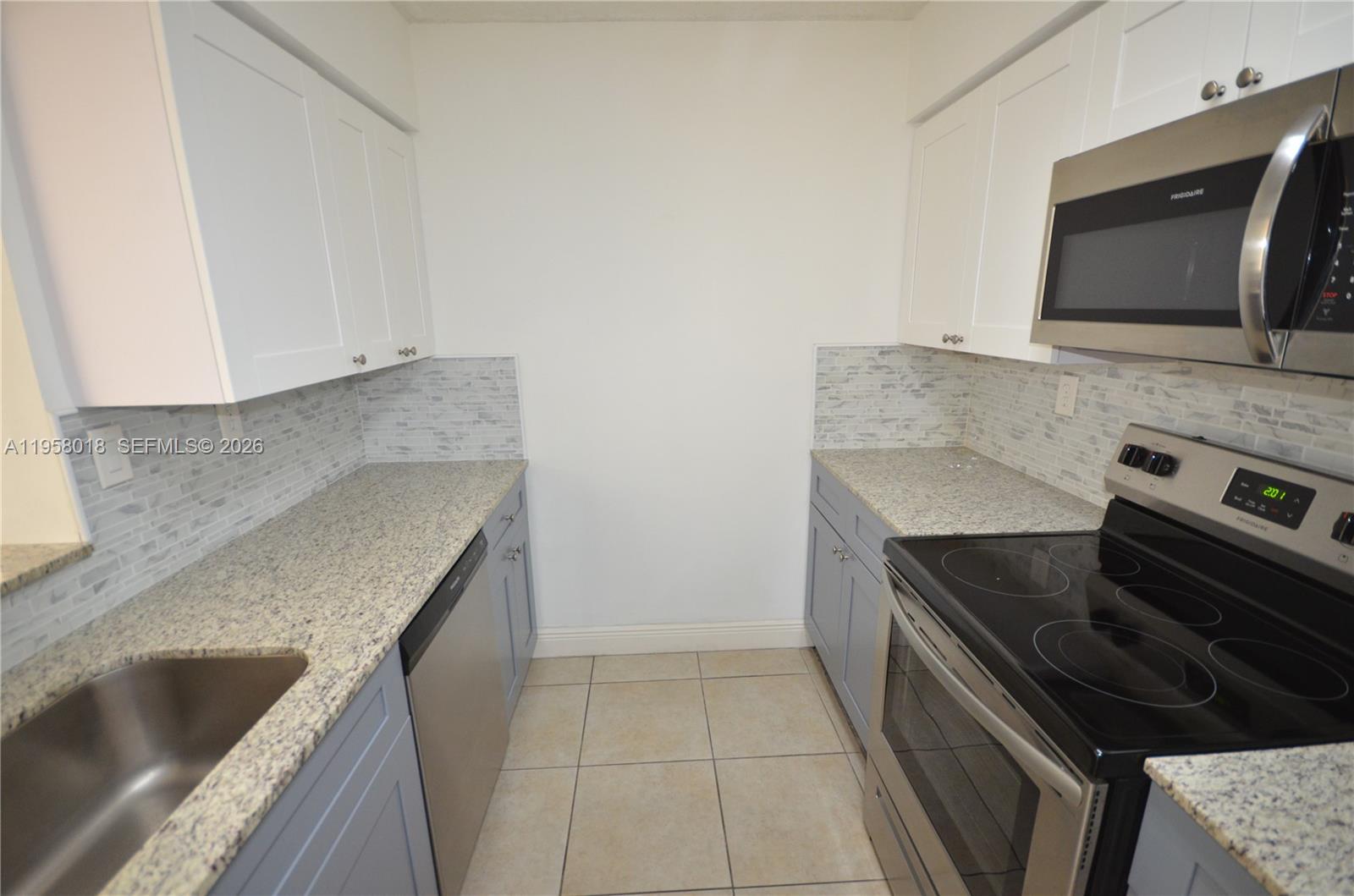 15201 Southwest 80th Street, Unit 207 Miami, FL 33193 - Photo 14 of 19 a kitchen with granite countertop a sink and a stove top oven