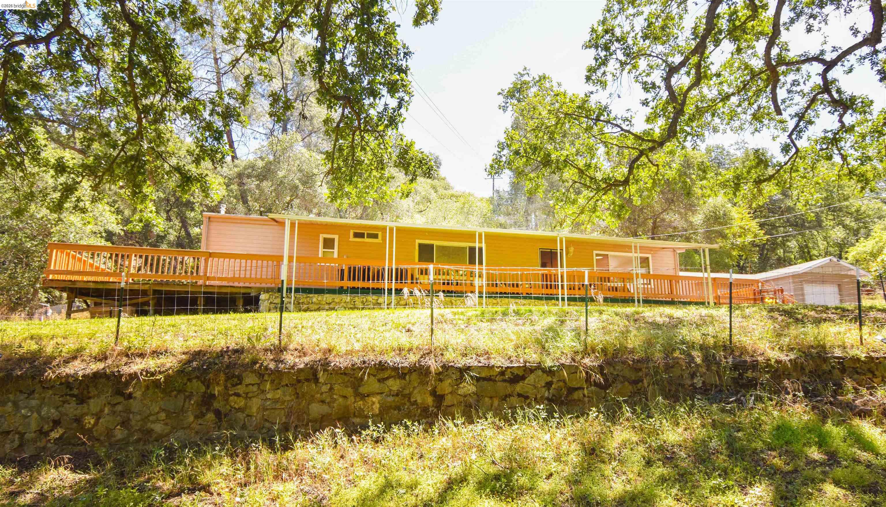 13904 Tuolumne Road Sonora, CA 95370 - Photo 37 of 44 Single-story residence featuring light-colored siding and a full-length wooden deck with railing