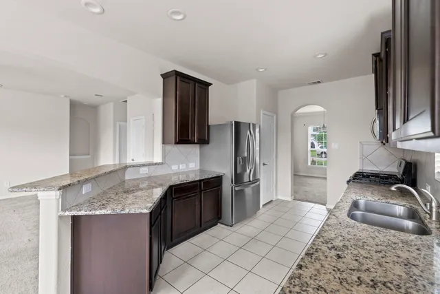 a kitchen with granite countertop a sink stove and refrigerator