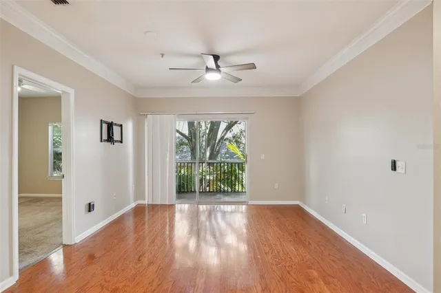 a view of an empty room with wooden floor and a window