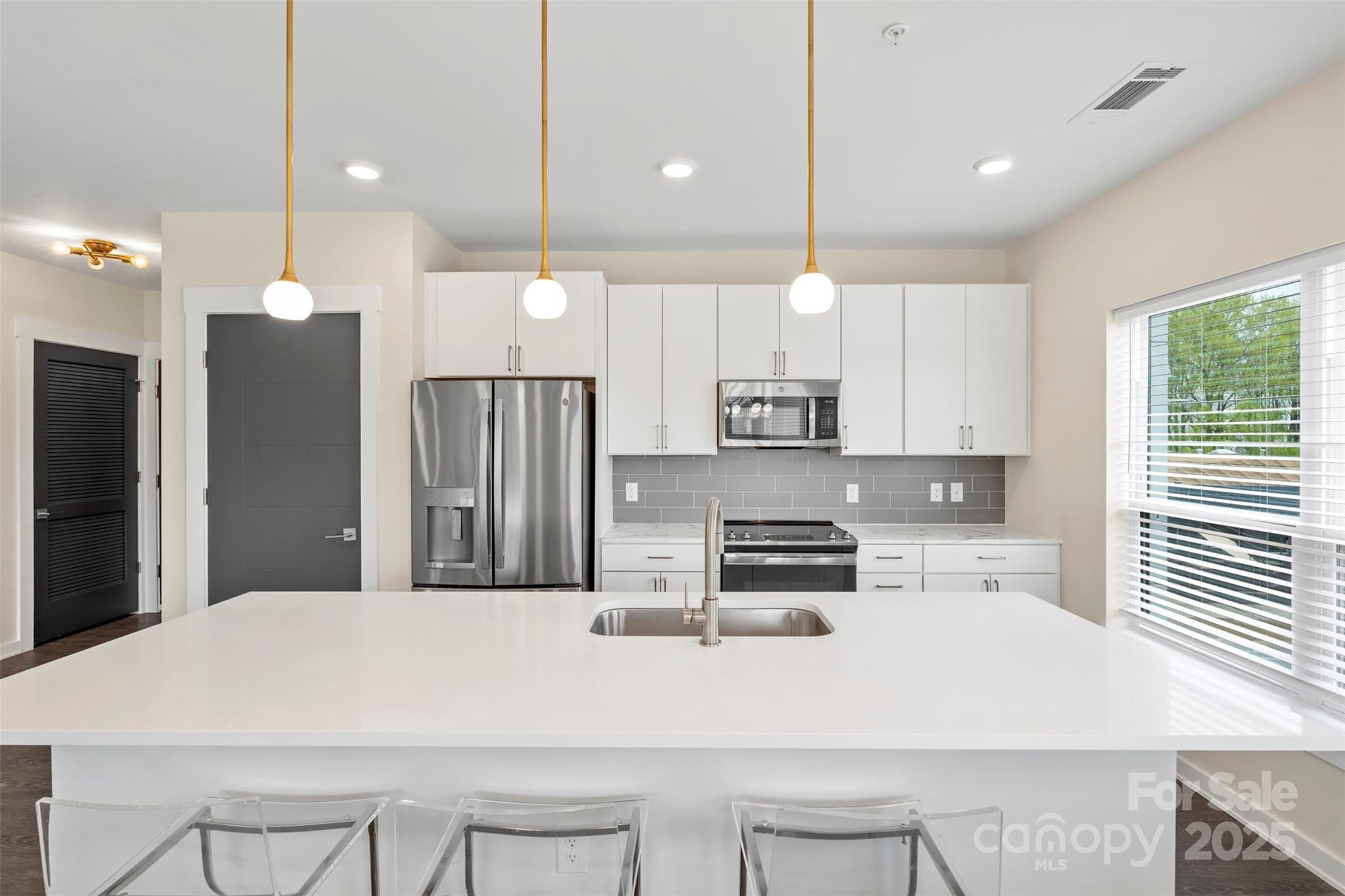 3630 North Davidson Street, Unit 3301 Charlotte, NC 28205 - Photo 6 of 33 a kitchen with kitchen island a refrigerator a stove a sink and chairs with wooden floor