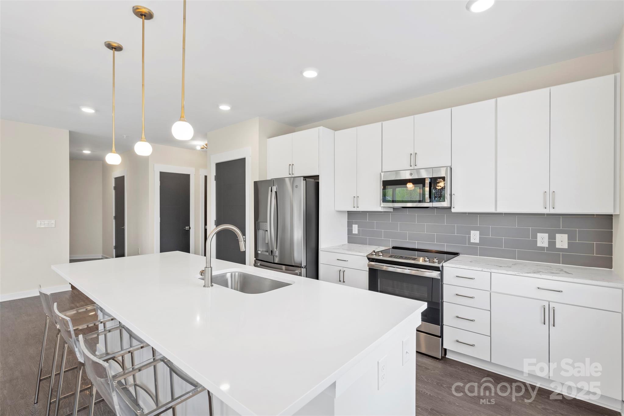 3630 North Davidson Street, Unit 3301 Charlotte, NC 28205 - Photo 7 of 33 a kitchen with stainless steel appliances a stove a sink a refrigerator a white table and chairs