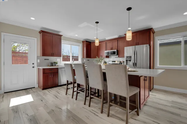 a kitchen with stainless steel appliances a dining table chairs stove and refrigerator