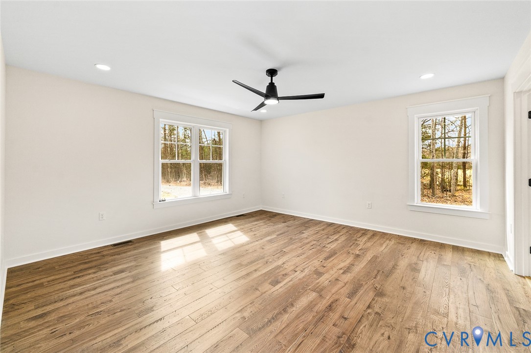 235 Bumpass Road Bumpass, VA 23024 - Photo 20 of 28 an empty room with wooden floor ceiling fan and windows