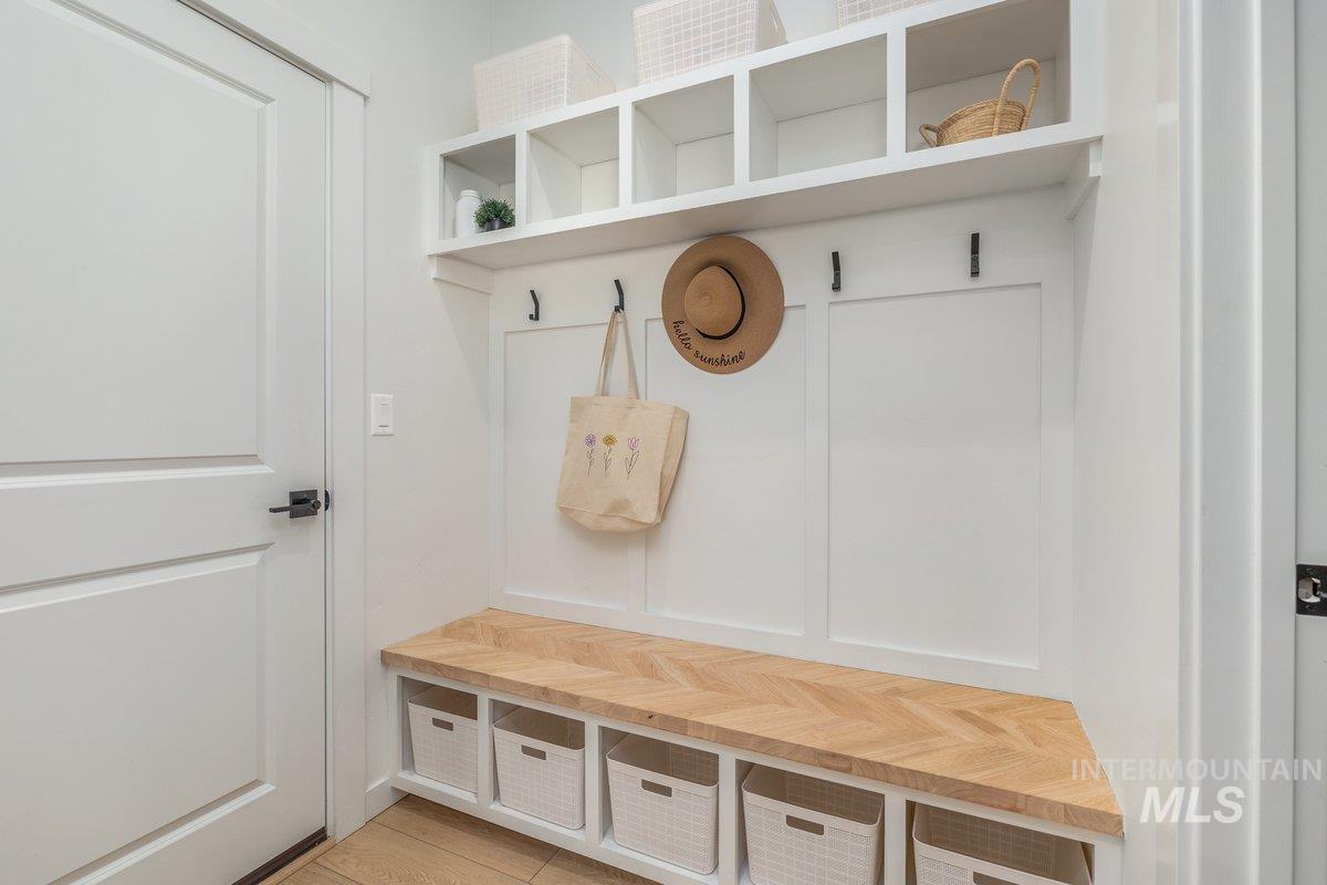 1380 West Chilitna Street Meridian, ID 83642 - Photo 40 of 50 Built-in mudroom bench featuring a wood-finish herringbone pattern, integrated storage cubbies, white paneling, and upper open shelving with white cabinetry