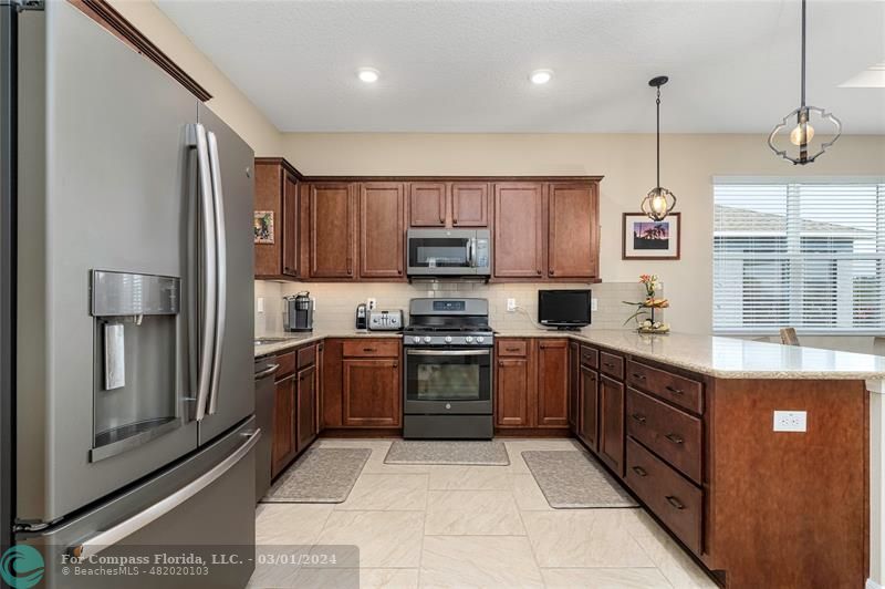 9857 Southwest 99th Loop Ocala, FL 34481 - Photo 11 of 45 a kitchen with stainless steel appliances granite countertop a refrigerator a sink and a stove