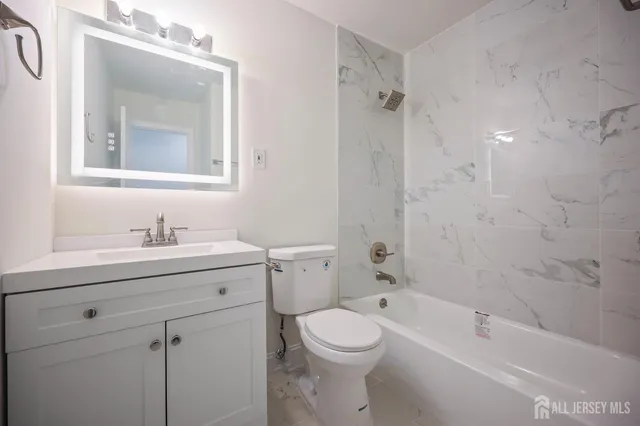 a bathroom with a granite countertop sink a toilet and shower