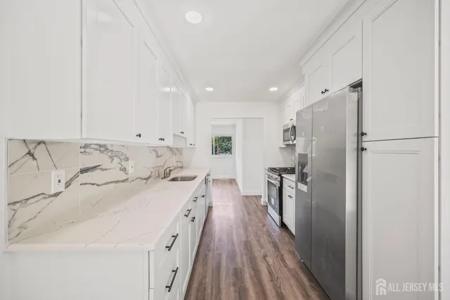 a large white kitchen with a stove a refrigerator a sink dishwasher and a oven with wooden floor