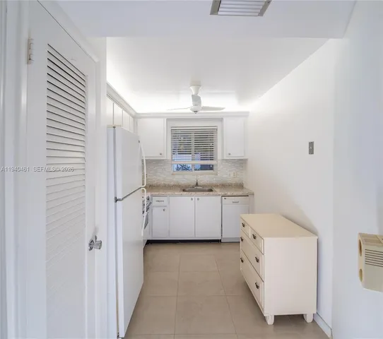 a kitchen with a refrigerator and white cabinets