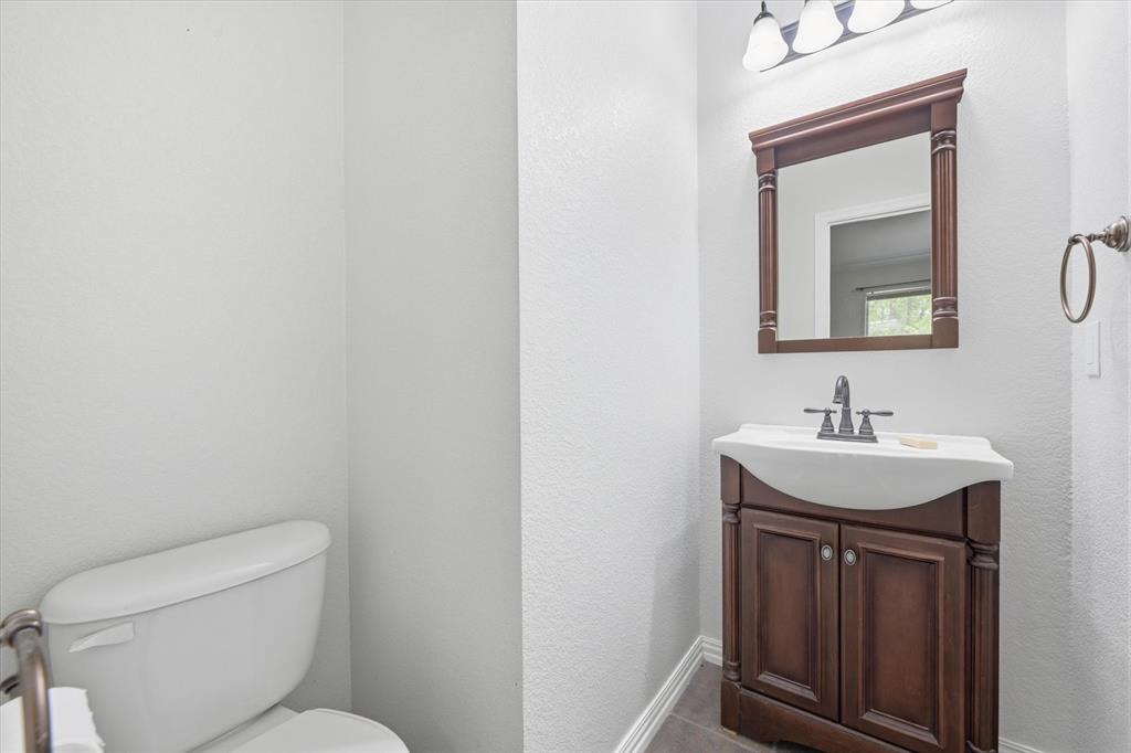 5992 Red Bud Road Fort Worth, TX 76135 - Photo 25 of 40 a bathroom with a toilet a sink a mirror and vanity