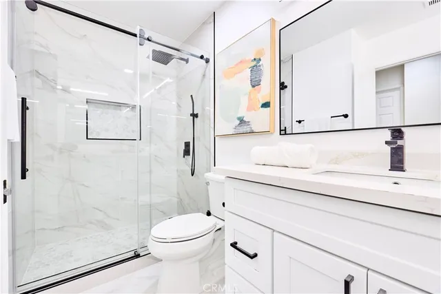 a bathroom with a shower sink vanity and toilet