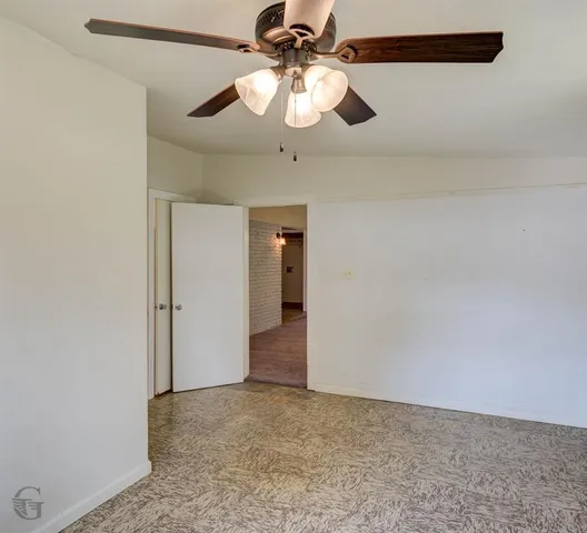 an empty room with a window and a ceiling fan